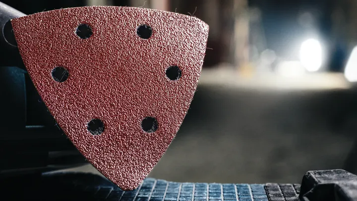 Detail view of a triangular sanding pad attached to a power tool.