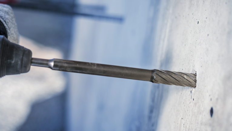 Rotary hammer drill making a precise hole in a concrete wall.