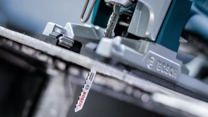 Close-up of a jigsaw blade cutting through a metal sheet.