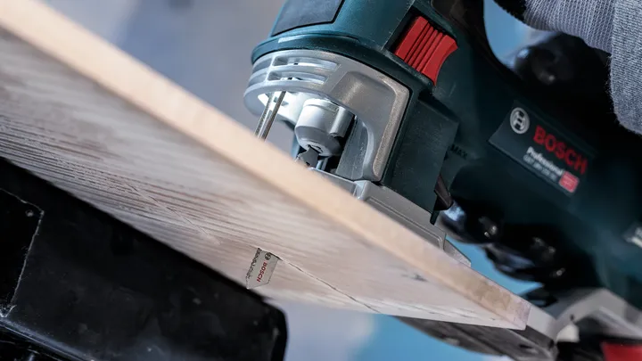 Person guides a jigsaw to cut through a wooden board.