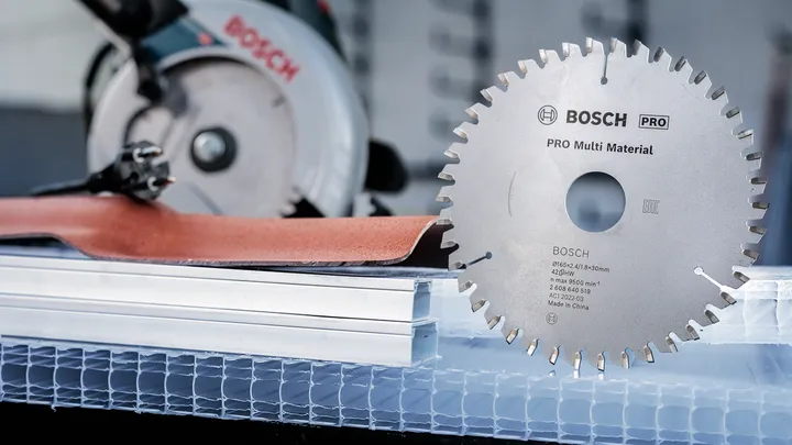 Circular saw blade next to power tool and construction materials.