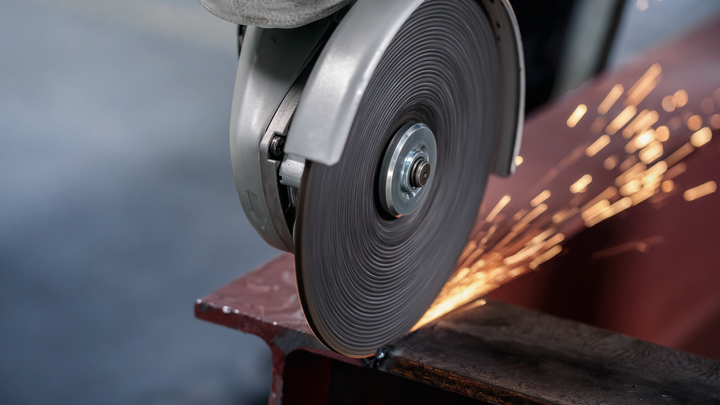 Metal cutting saw creating sparks as it slices through a steel beam.