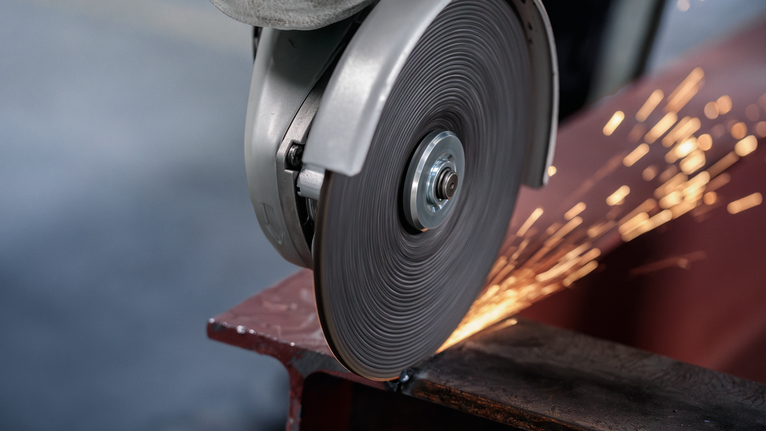 Metal cutting saw creating sparks as it slices through a steel beam.