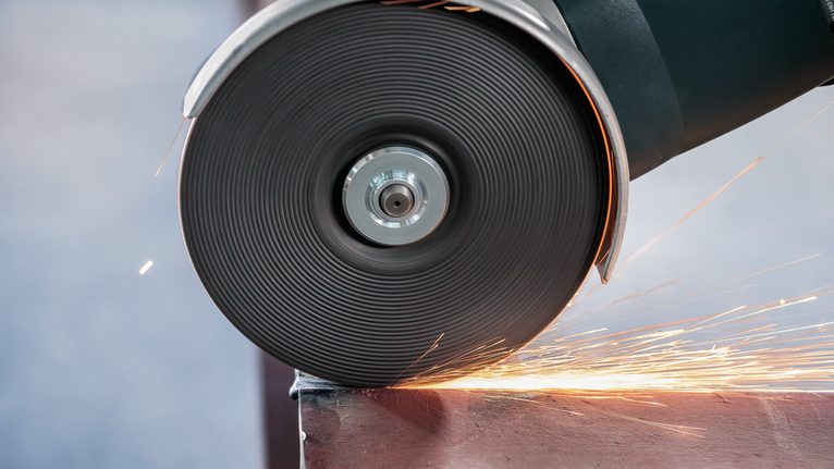 Cutting wheel grinds metal, sending sparks across the work surface.