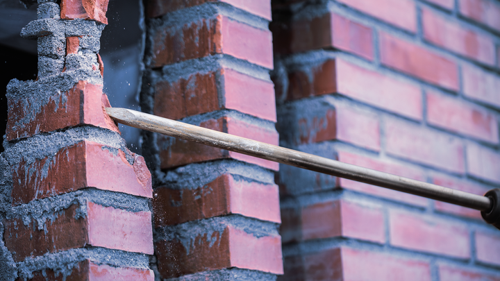 Chisel tool demolishing a brick wall.