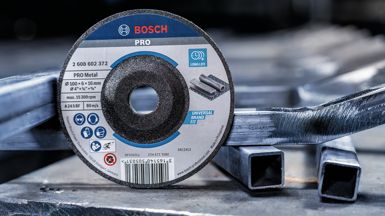 Cutting disc placed on stacked metal pipes in an industrial setting.