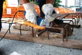 A person wearing safety equipment uses an angle grinder to cut rebar on a construction site.