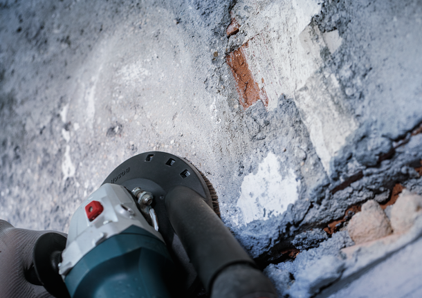 Bosch concrete grinding cup removing mortar from wall.