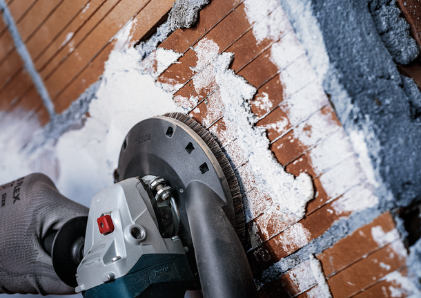 Bosch diamond grinding cup removing plaster from brick wall.