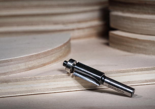 Router bit placed on layered plywood, ready for woodworking applications.