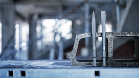 Two metal chisels stand upright in a concrete block on a construction site.