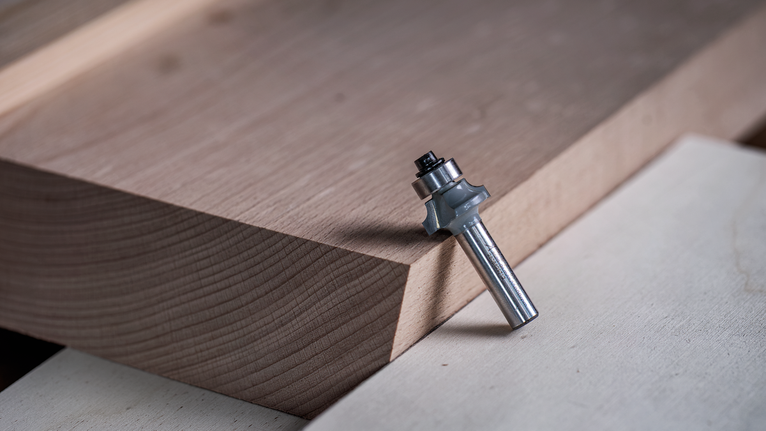 Router bit positioned on stacked wooden boards.