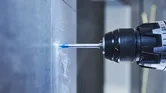مثقاب كهربائي يُحدث ثقبًا في جدار مُبلّط.