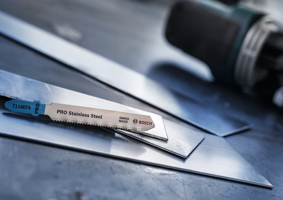 شفرة المنشار الكهربائي ترتكز على صفائح الفولاذ المقاوم للصدأ في ورشة عمل.