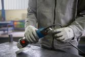 A person wearing safety equipment prepares to plug in an angle grinder.