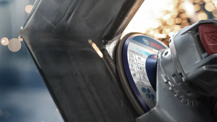 Angle grinder cutting through metal, sparks flying from the point of contact.