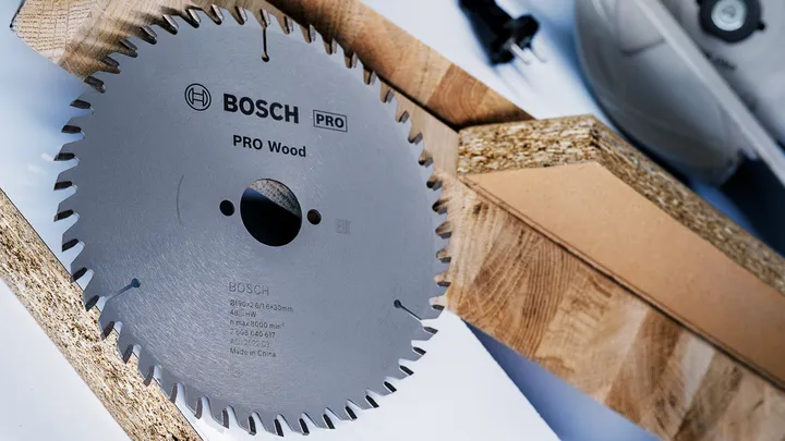 Circular saw blade placed beside wooden planks on a work surface.
