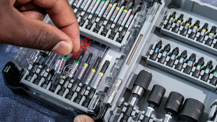Person selects a screwdriver bit from an organized tool kit.