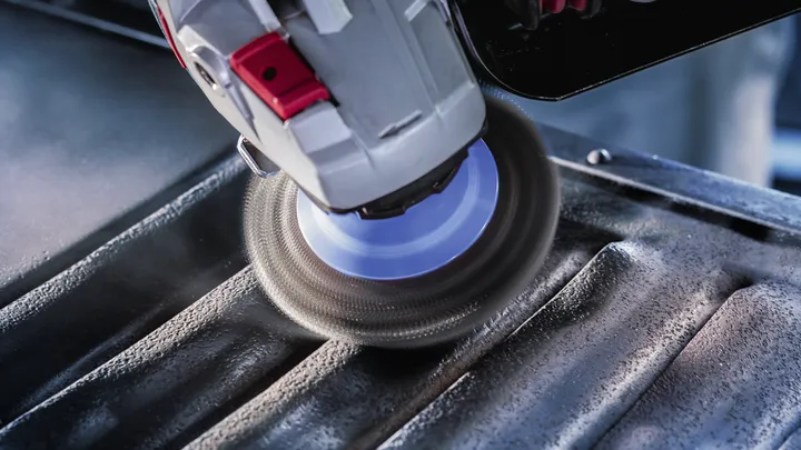 Angle grinder polishing grooves on a metal surface.