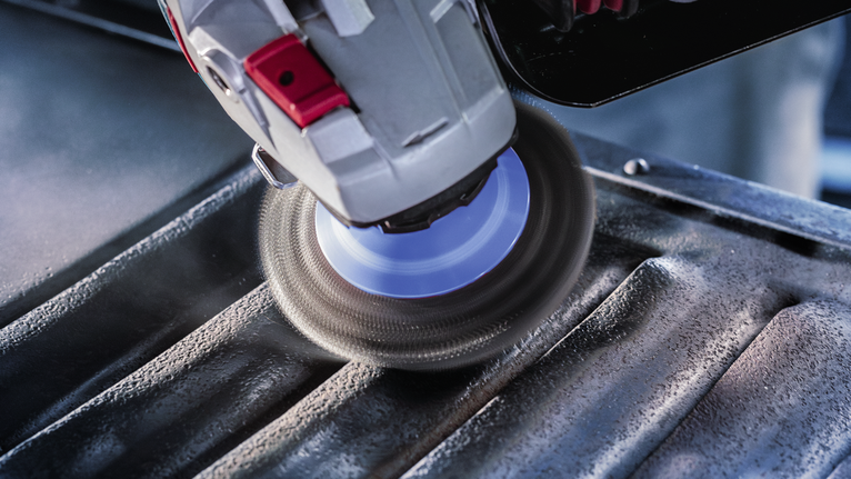 Angle grinder polishing grooves on a metal surface.