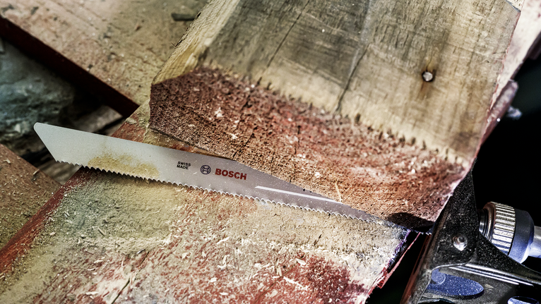 Saw blade cutting through a thick piece of wood in a workshop.