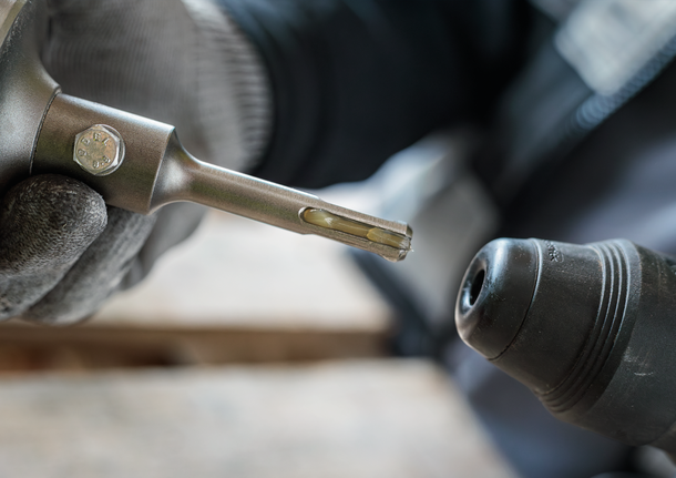 Person wearing safety equipment inserting a drill bit into a rotary hammer.