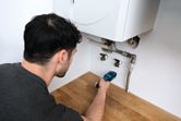 Person checking moisture level in wood countertop near plumbing under a boiler.