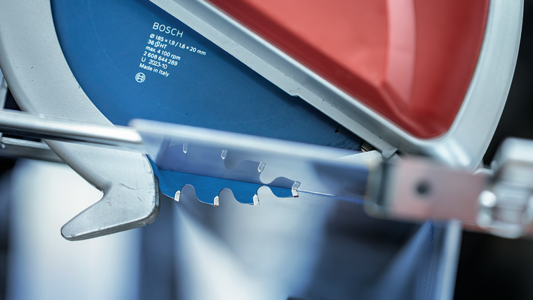 Circular saw blade positioned for cutting, with metal guard partially raised.