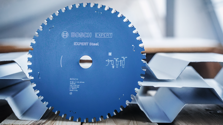 Circular saw blade placed upright on corrugated metal sheets.