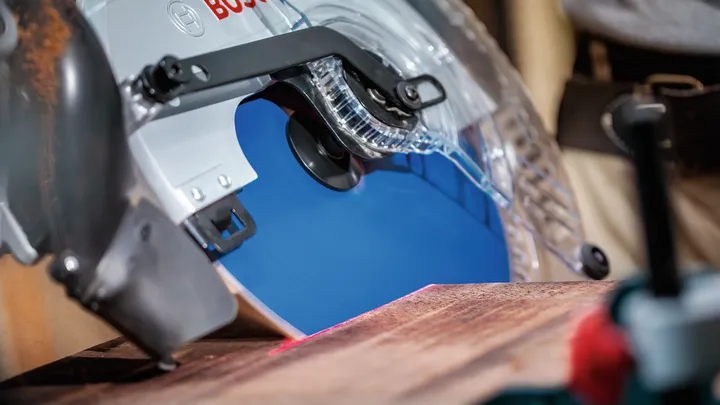Circular saw cutting through a wooden board in a workshop.