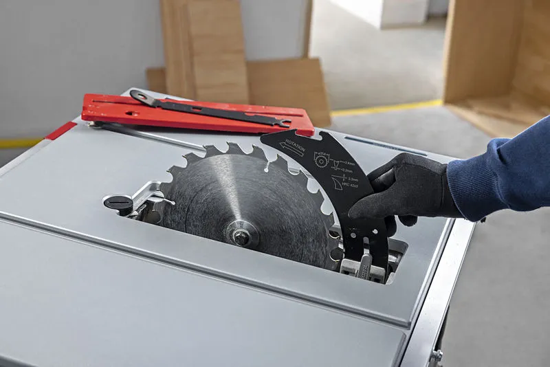 Person wearing safety equipment changing a blade on a table saw.