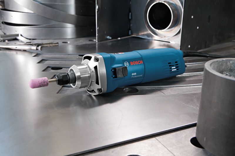 Straight grinder with a mounted abrasive point rests on a metal work surface.