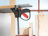 Morsetto accessorio del sistema che fissa una tavola di legno a una superficie metallica in un'officina.