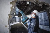 Operaio che perfora un muro di cemento.