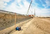 Livella laser installata in un cantiere edile, con una gru sullo sfondo.
