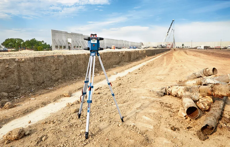 Livella laser installata su un treppiede in un grande cantiere.