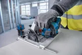 Una persona che indossa un equipaggiamento di sicurezza aziona una sega circolare per tagliare un pannello.