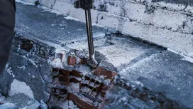 Strumento di demolizione che rompe il cemento su un muro di mattoni.