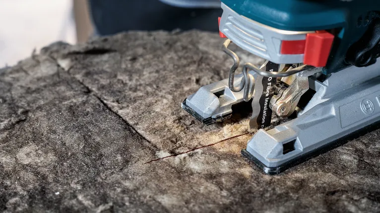 Un seghetto alternativo che esegue un taglio dritto su una superficie di legno ruvida.