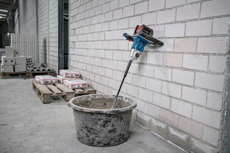 Un agitatore senza fili mescola il materiale in un secchio in un cantiere edile.