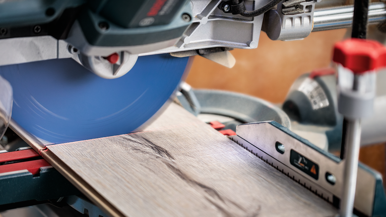 Sega troncatrice scorrevole che taglia assi di legno su un banco da lavoro.