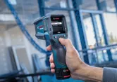 Persona che utilizza un rilevatore di calore con display digitale in un cantiere edile.