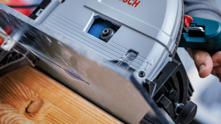 Una persona guida una sega circolare lungo una tavola di legno.