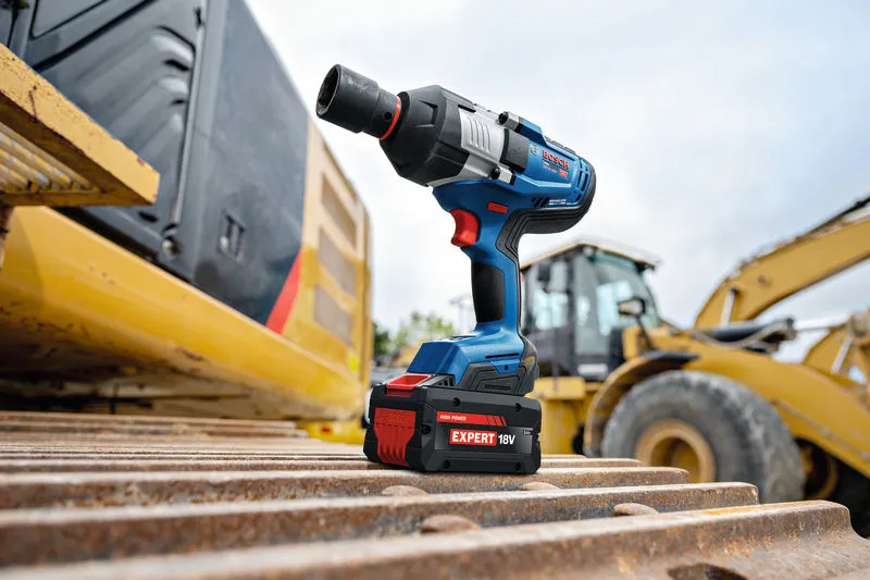 Chiave a impulsi a batteria appoggiata su attrezzature pesanti in un cantiere edile.
