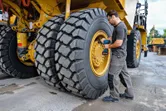Una persona che indossa un equipaggiamento di sicurezza utilizza una chiave a impulsi senza fili su uno pneumatico di un camion di grandi dimensioni.