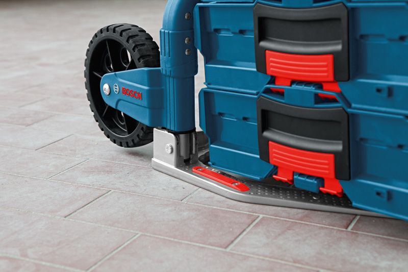 Carrello pieghevole con cassette degli attrezzi impilate, appoggiato su un pavimento piastrellato.