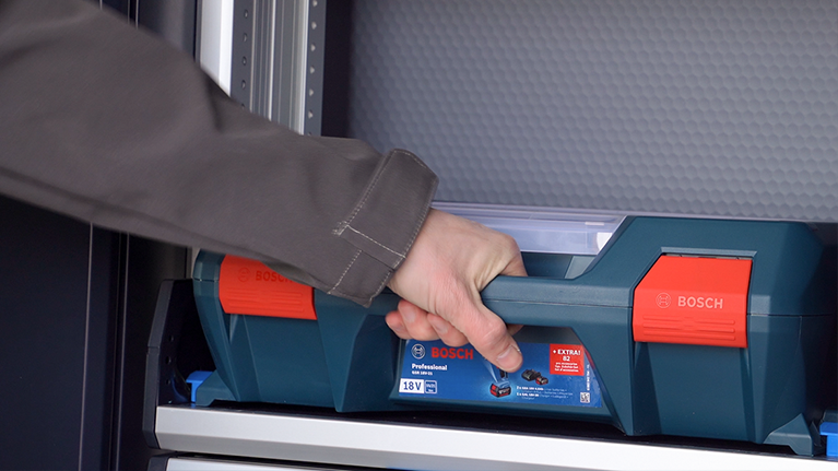 Una mano afferra una cassetta degli attrezzi Bosch Professional blu e rossa.