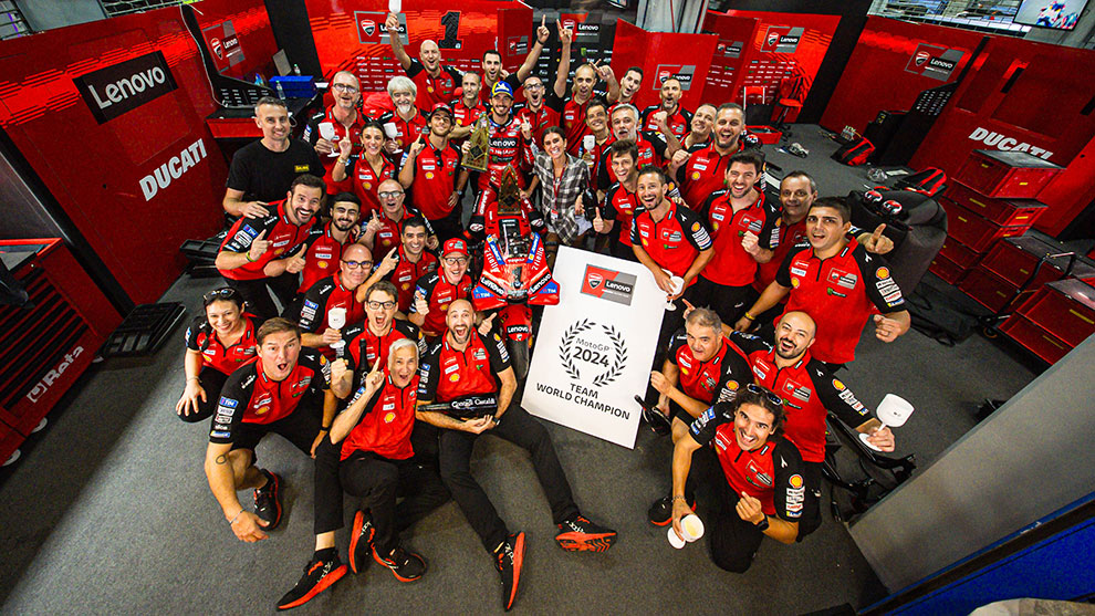 Un team Ducati festeggia il titolo di campione del mondo 2024, indossando magliette rosse.