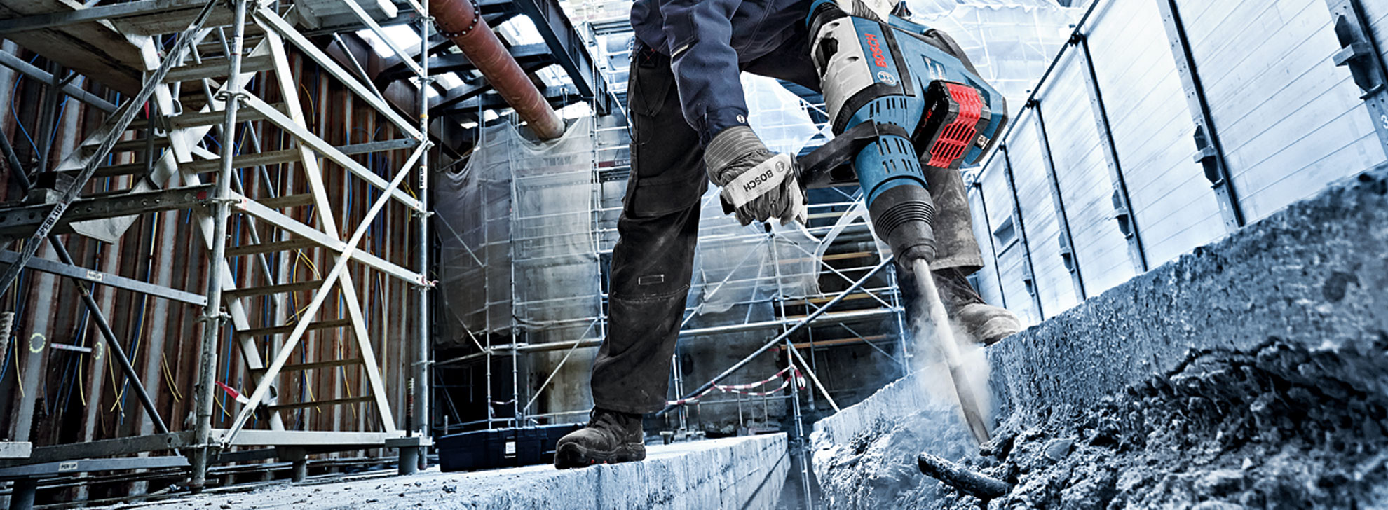 Un operaio usa un martello pneumatico Bosch in un cantiere polveroso.