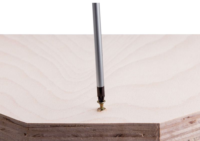 Screwdriver driving a screw into light-colored wood panel.